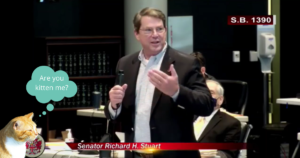 orange cat with a tipped ear with thought bubble, "Are you kitten me?" over image of Senator Richard Stuart